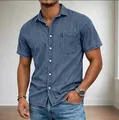 Close-up detail of a men's blue denim short-sleeve button-down shirt with chest pocket - Aqua