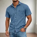 Detailed view of men's short-sleeved blue denim casual shirt with front pocket detail. - Teal