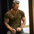Close-up of men's brown short-sleeve Henley t-shirt featuring buttoned neck detail. - Brown