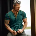 Close-up of a men's dark teal short-sleeved Henley T-shirt with contrast stitching detail - S / Tops / Malachite green