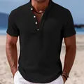 Detail view of men's black linen short sleeve shirt with stand collar on a beach. - S / Tops / Black