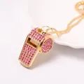 Dettaglio di un ciondolo a fischietto dorato con strass rosa molto scintillanti - Collana Fischietto Strass Rosa / Oro