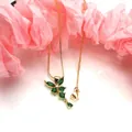 Dettaglio di un elegante ciondolo a farfalla dorato con vivaci zirconi marquise verdi - Set Collana con Ciondolo / Verde