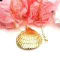 Close-up of elegant golden scallop shell pendant necklace on a pink floral backdrop - Radial Scallop Necklace (4) / Pendant and Necklace Set