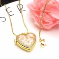 Close-up of golden heart locket necklace with pink enamel and zircon accents - Yellow + Necklace