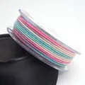 Macro view of 1.2mm multicolor gradient cotton cord with metallic glitter on a transparent spool - 1.2mm / 21# Pink Blue Purple Beige White