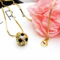 Nahaufnahme der goldenen Fußball-Halskette mit funkelndem Zirkonia-Anhänger - Halsketten-Set / Schwarz