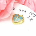 Macro detail of a gold-plated heart-shaped pendant with blue enamel and zircon inlay. - Heart Pendant / Blue