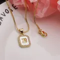 Detailed macro view of gold letter B pendant necklace with white shell inlay and zirconias - Letter B