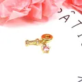 Makro-Detail eines goldenen Zirkon-Hundeknochen-Anhängers und rosa Herz-Kristall-Anhängers - Hundeknochen und Rosa Herz