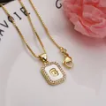 Detail of square gold-plated necklace pendant featuring a shell inlay and letter G - Letter G