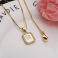 Close-up of square gold pendant with shell inlay and zircon-set letter N - Letter N