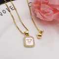 Detail of gold-plated square pendant necklace with shell inlay and letter V. - Letter V