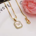 Close-up of gold square pendant featuring letter W on white shell with zircon border - Letter W