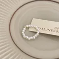 Vista dettagliata di un elegante anello di perle minimalista con una perla dorata - Stile elastico con perline / Perla con perline dorate