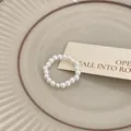Dettaglio di un elegante anello di perle su un piatto di ceramica con cartolina. - Stile elastico con perline / Perla con perline argentate