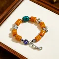 Vintage ethnic style orange bead bracelet featuring a turquoise stone and silver elephant charms - Imitation Amber Spacers: Magpie on Plum Branch Buckle Bracelet