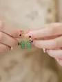 A close-up view of handmade aventurine green stone dangle hoop earrings held in hands - Three Beads Earrings