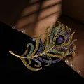 Close-up of a vintage gold peacock feather brooch with colorful rhinestones and purple gem. - Multicolor Peacock Feather Style
