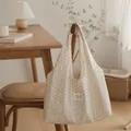 Elegant cream tote bag with star patterns shown in a cozy interior lifestyle setting - Beige with Brown Stars
