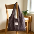 Detail view of a slouchy canvas tote bag with a star pattern hanging on a wooden chair - Dark Coffee with Small Stars