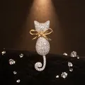 Primer plano de un broche de gatito brillante con pedrería y lazo dorado en terciopelo. - Gato Dorado
