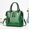Elegant green crocodile-patterned patent leather handbag with gold-tone hardware detail. - Green