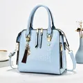 Detail view of light blue crocodile embossed patent leather handbag with gold hardware - Light Blue