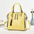 Stylish yellow crocodile pattern patent leather handbag with tassel charm shown in setting - Yellow