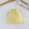 Gros plan d'une pochette à cordon en vichy jaune avec une étiquette de marque May Rabbit. - Plaid Jaune