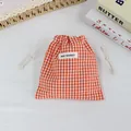 Gros plan d'un pochon orange à carreaux avec cordon pour le rangement de petits objets - Grille Orange