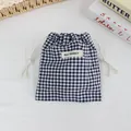 Detail view of blue and white gingham drawstring storage pouch with May Rabbit label - Navy Blue Plaid