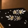 Primer plano detallado de alfileres de cuello de hoja de trigo plateados sobre terciopelo negro - Plateado