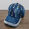 Dettaglio del cappellino da baseball in denim blu decorato con strass a goccia in cristallo - Celeste