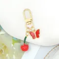 Primo piano di un portachiavi decorativo con ciliegia rossa e farfalla con strass scintillanti. - Ciliegia (Ciliegia 1)