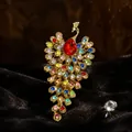 Vista detallada del lujoso broche de pavo real con strass de colores sobre fondo de terciopelo. - Broche de Pavo Real / Oro Rubí