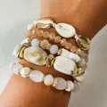 Primer plano de pulseras de cuentas bohemias con dijes de caracoles dorados y blancos - Pulsera Beige