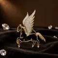 Nahaufnahme der goldfarbenen Pegasus-Brosche mit kristallbesetzten Flügeln auf Samt - Hohle Pegasus Brosche