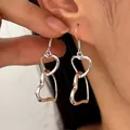 Stylish minimalist silver double linked heart dangle earrings shown on an ear for women - Double Heart / Silver