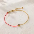 Detailansicht eines Armbands mit goldener Kette, roter Schnur und klarem Zirkonstein. - Strass Armband (A74) / Gold