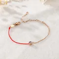 Detail eines Armbands aus roter Kordel und Goldkette mit funkelndem Zirkonstein. - Strass Armband (A76) / Roségold
