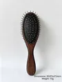 Close-up detail of wooden texture hairbrush featuring silver-colored metal massage bristles - Brown