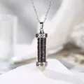 Close-up of a silver-colored cylindrical necklace pendant filled with garnet crushed stones. - Garnet