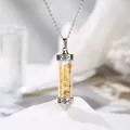 Macro view of citrine crushed stones in a cylindrical glass pendant engraved with Love - Citrine