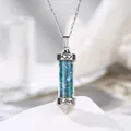 Close-up of a glass cylinder pendant filled with blue natural crushed stones and Love engraving - Apatite