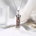 Detailed close-up of a cylindrical pendant filled with colorful natural crystal gravel. - Tourmaline