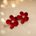 Detailed macro view of matte red flower earrings with elegant gold textured centers - Red