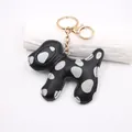 Detail of a Dalmatian dog-shaped leather keychain with polka dots and gold clasp. - Black Keychain Style