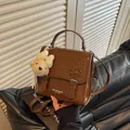 Close-up view of a brown preppy style backpack featuring a cute plush teddy bear charm - Coffee (With Charm)