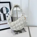 Close-up detail of a white bubble quilted dumpling bag with stylish ruffled shoulder strap - White
